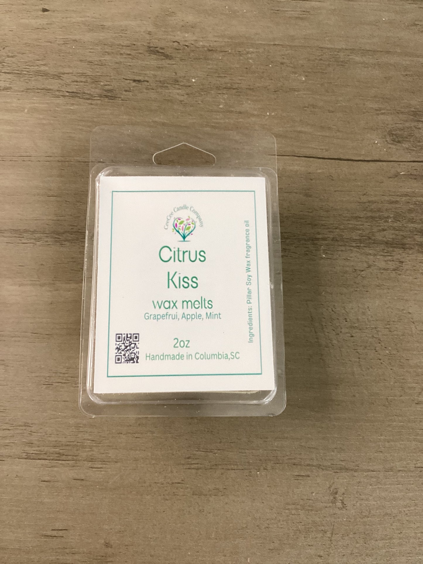 A 2 oz Citrus Kiss Soy Wax Melt by CeeCee Candle Company sits on wood, featuring grapefruit, apple, and mint scents. Handmade in Columbia, SC—perfect for your Build Your Own Wax Melts Bundle or customizing your scent mix.