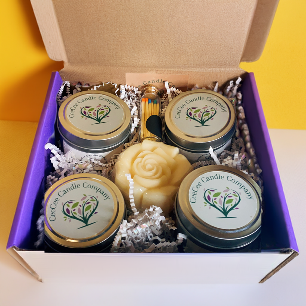 The CeeCee Candle Company Gift Box by CeeCee Candle Company features three labeled soy candles, a rose-shaped candle, a match jar, and white filler—beautifully arranged for the perfect self-care gift.