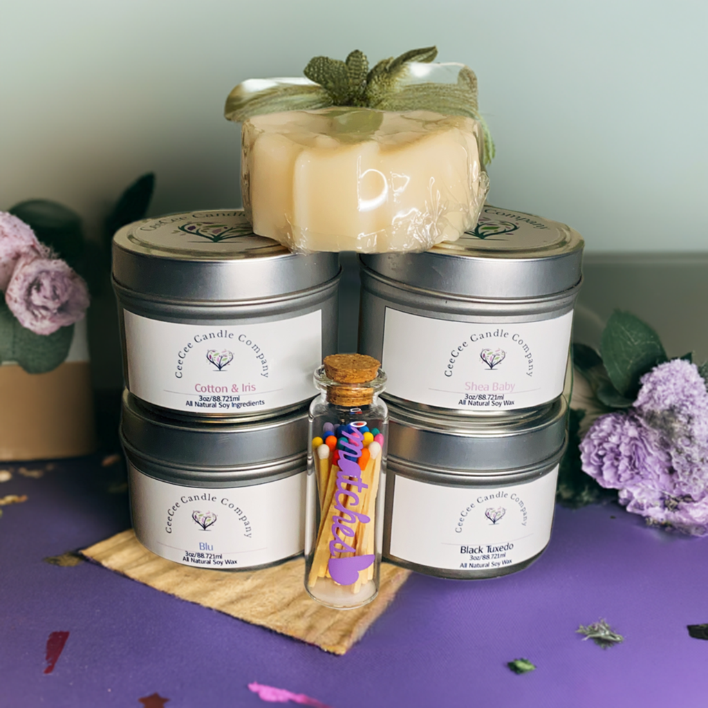 The CeeCee Candle Company Gift Box by CeeCee Candle Company features four soy candles, artisanal soap, and a glass vial of matches, beautifully arranged with purple flowers—an ideal self-care gift displayed on a vibrant purple surface.