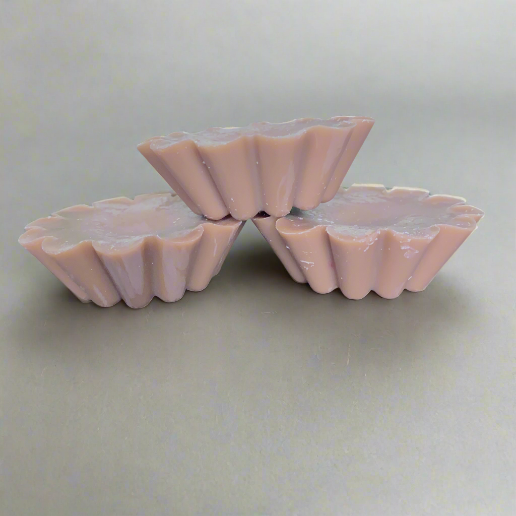 Three pink, scalloped Candle Tart Melts by CeeCee Candle Company are stacked in a small pyramid against a plain gray background.