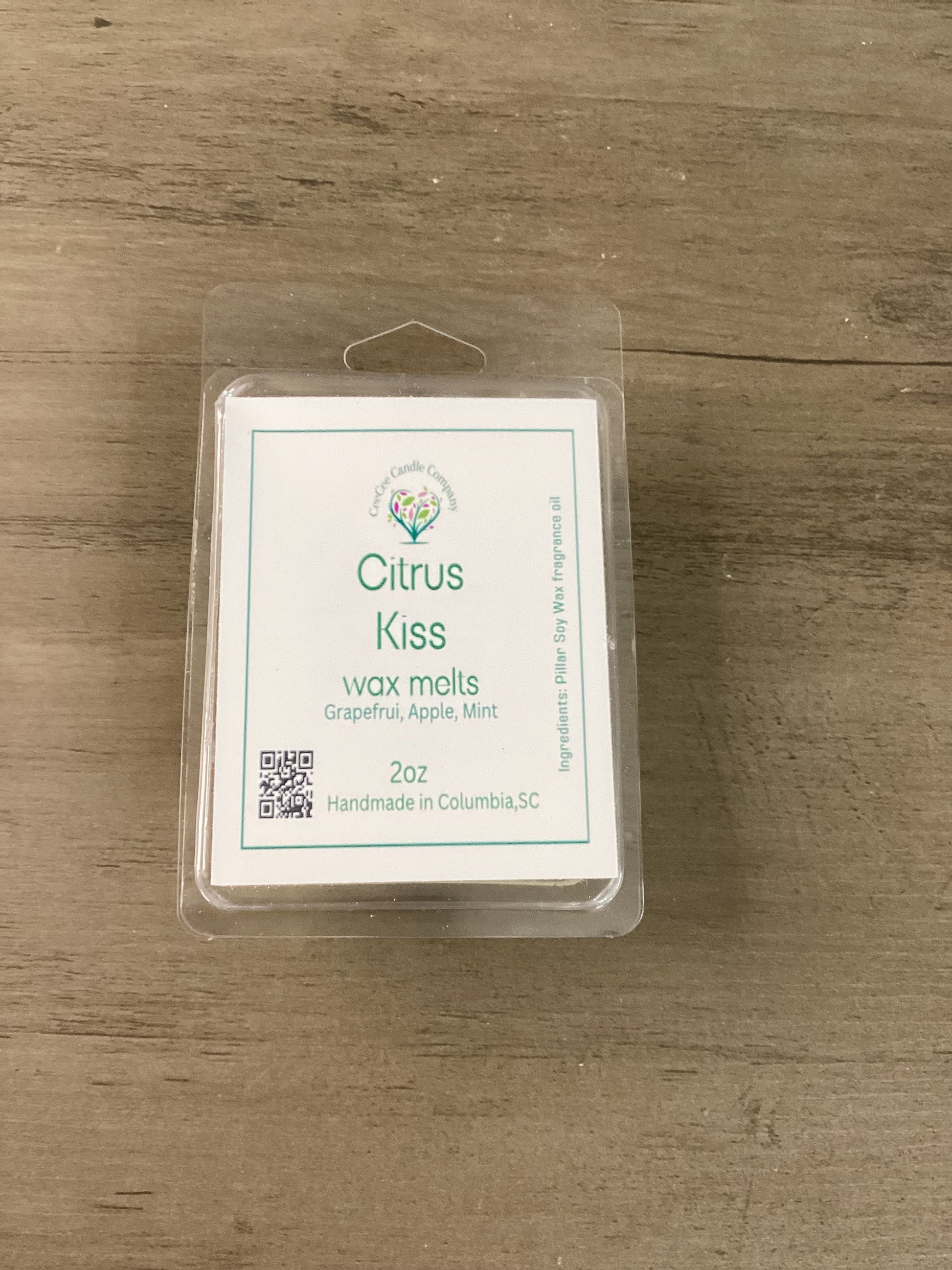 A 2 oz Citrus Kiss Soy Wax Melt by CeeCee Candle Company sits on wood, featuring grapefruit, apple, and mint scents. Handmade in Columbia, SC—perfect for your Build Your Own Wax Melts Bundle or customizing your scent mix.