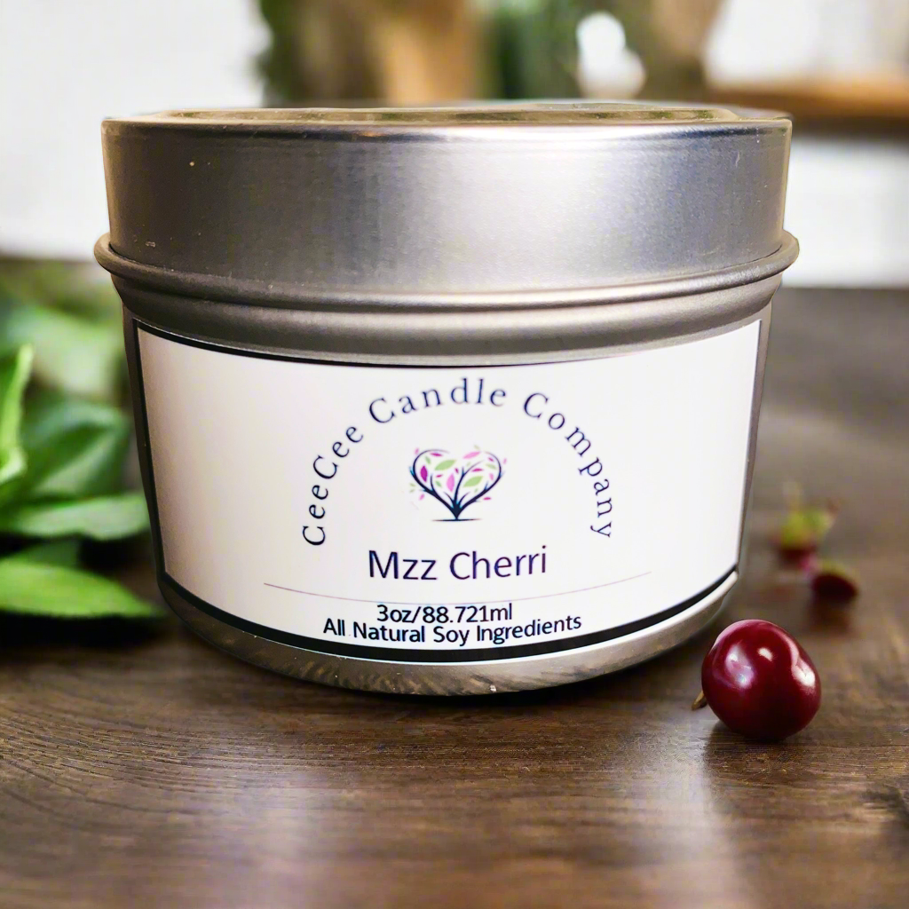 A 3oz CeeCee Candle Company Travel Size Soy Candle with all-natural soy wax and a mood-boosting cherry scent sits on wood, with cherries and green leaves nearby.