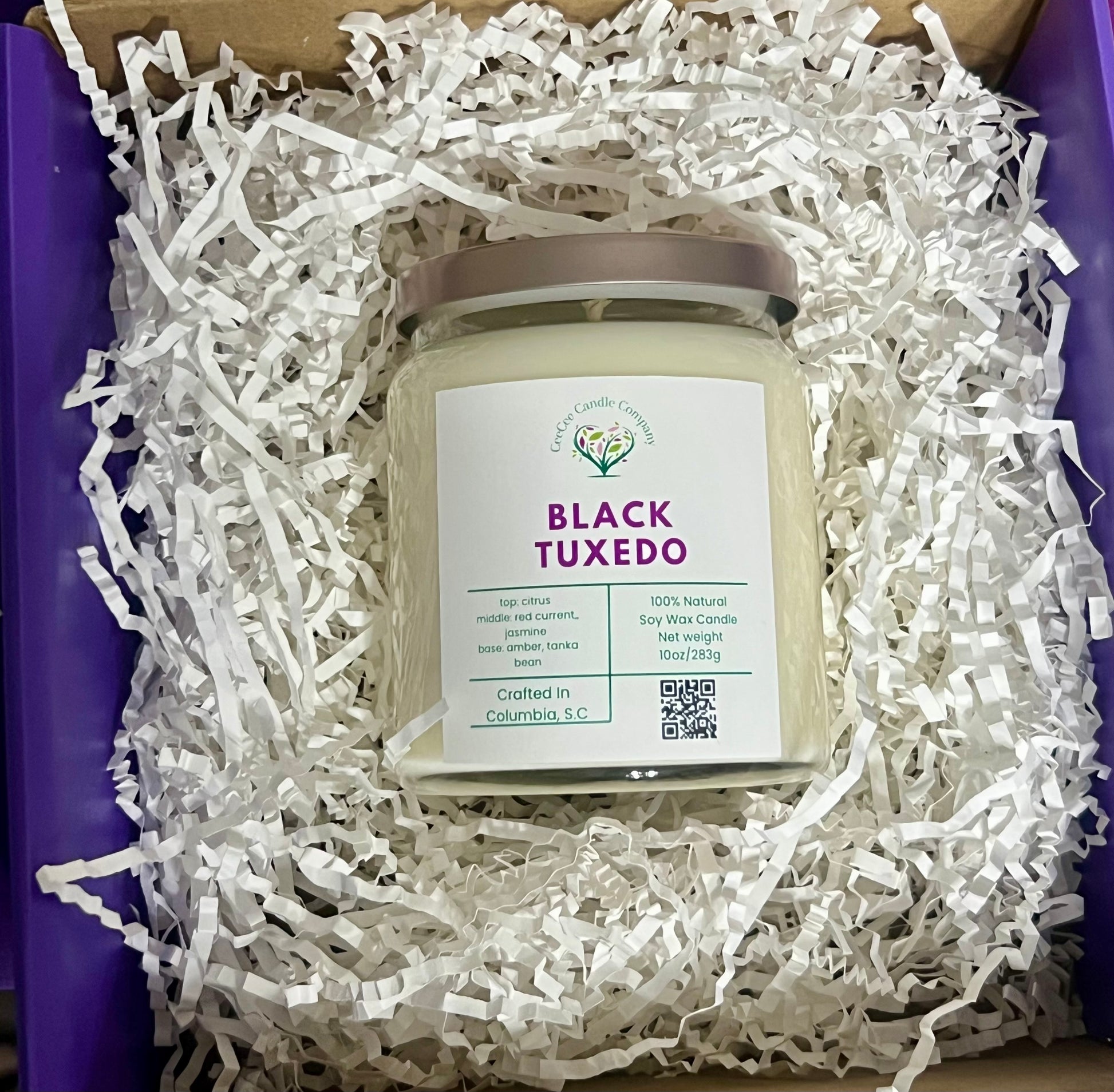 A CeeCee Candle Company Signature Apothecary Collection soy candle rests in white paper shreds inside a purple box. Made in Columbia, S.C. with premium fragrance oils by CeeCee Candle Company.