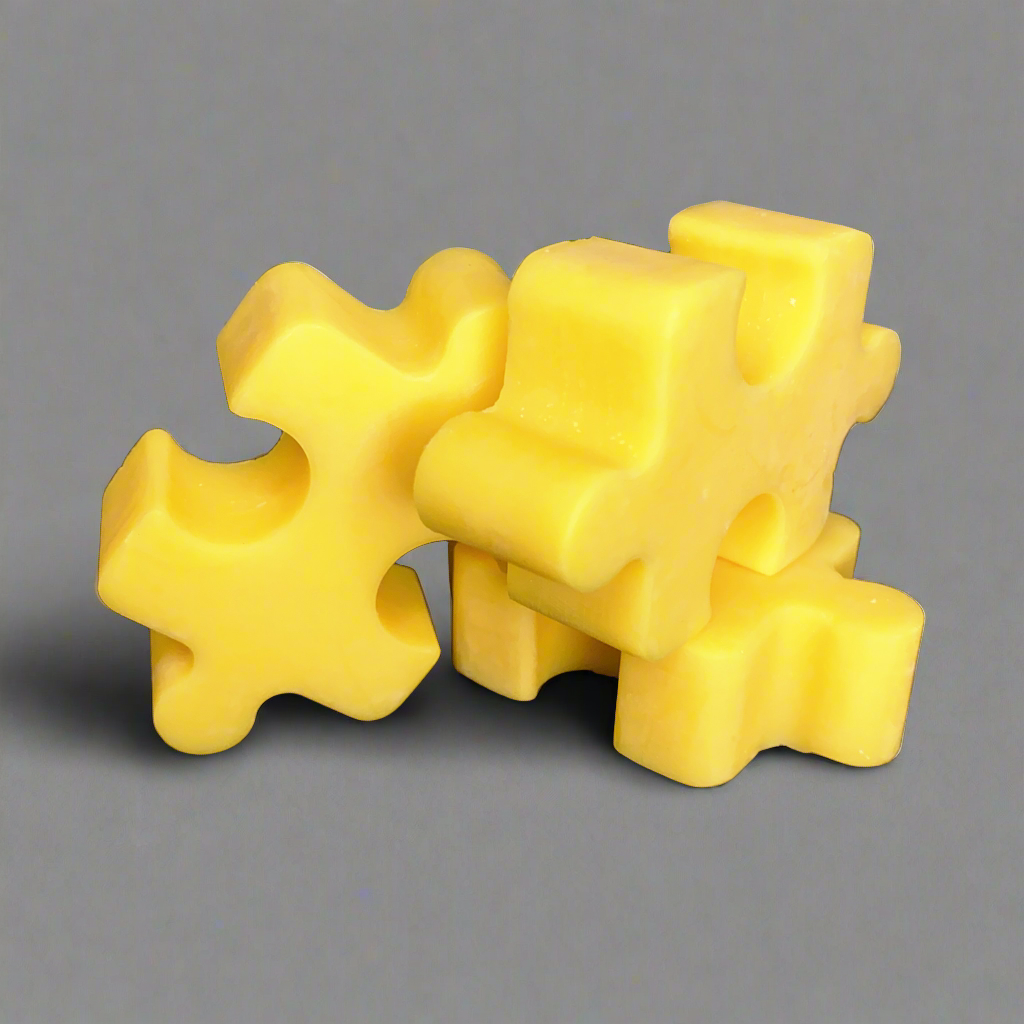 Three yellow Puzzle Pieces Wax Melts by CeeCee Candle Company, made of soy wax, are stacked together against a plain gray background.