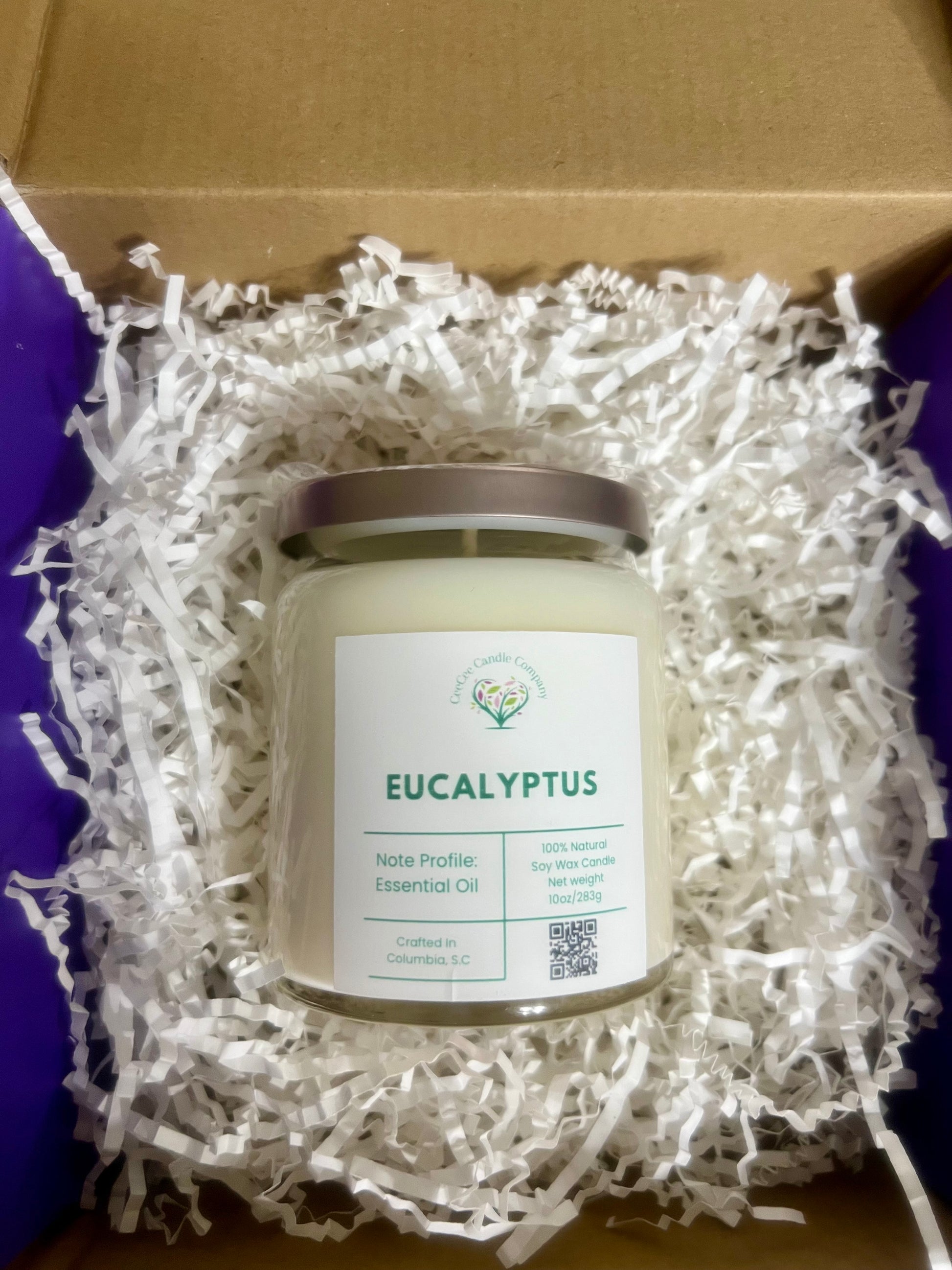 A CeeCee Candle Company Signature Apothecary Collection "Eucalyptus" soy candle sits in a box with white shreds. Made in Columbia, SC, it features 100% natural soy wax and premium fragrance oils.