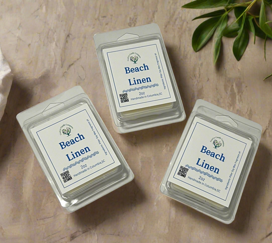 Three packs of CeeCee Candle Company Heart Shaped Wax Tarts are arranged on a beige surface with green leaves. Each handmade 2oz soy wax tart from Columbia, SC offers uplifting scents and features a QR code on the label.