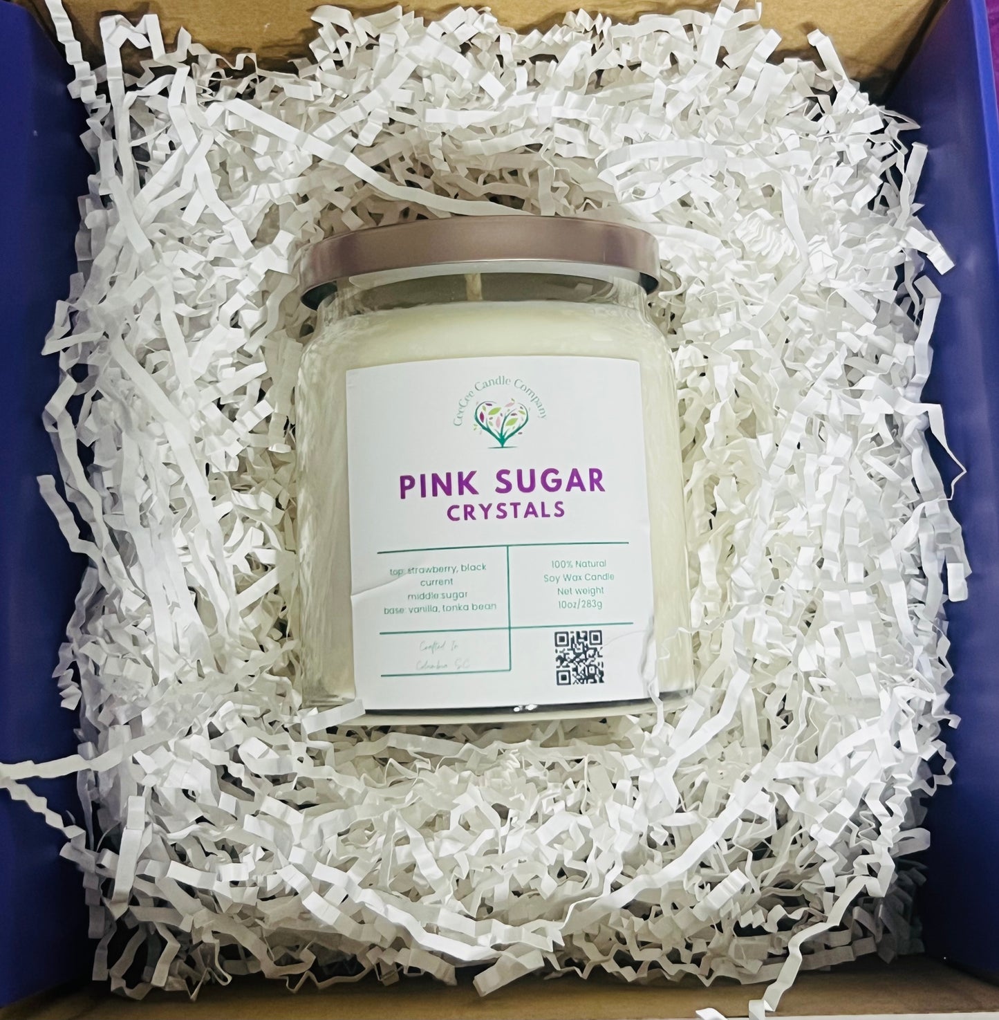A CeeCee Candle Company Signature Apothecary Collection candle labeled "Pink Sugar Crystals" with natural soy wax and premium fragrance oils comes boxed with white crinkle paper. The label includes logo, scent notes, QR code, and a light-colored lid.