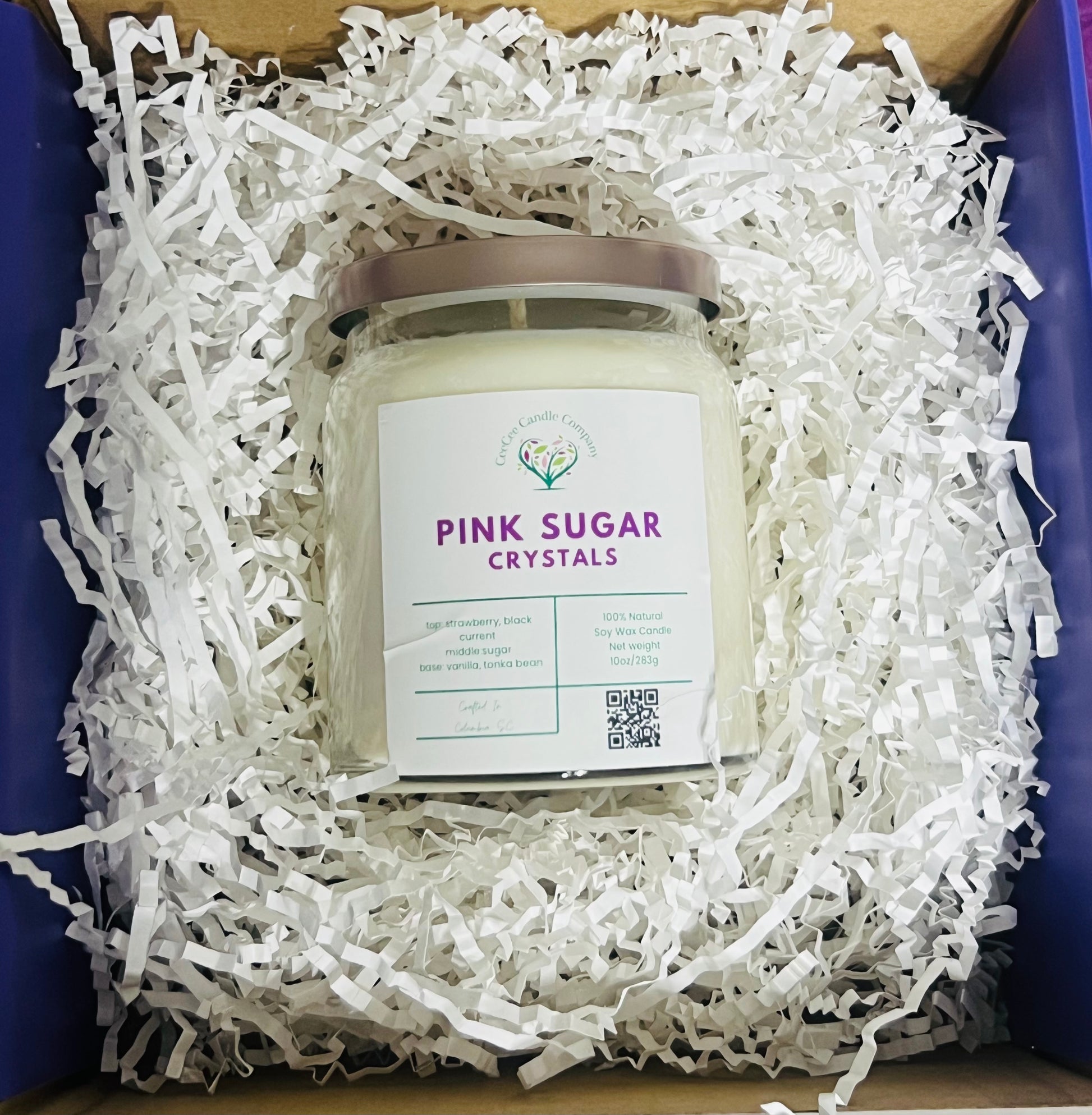 A CeeCee Candle Company Signature Apothecary Collection candle labeled "Pink Sugar Crystals" with natural soy wax and premium fragrance oils comes boxed with white crinkle paper. The label includes logo, scent notes, QR code, and a light-colored lid.