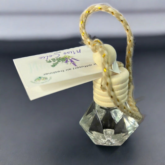 The CeeCee Candle Company Car Diffuser is a small hexagonal glass bottle with a wooden cap and braided string, featuring a floral tag. Made from natural materials, it freshens your car with a refreshing aroma.
