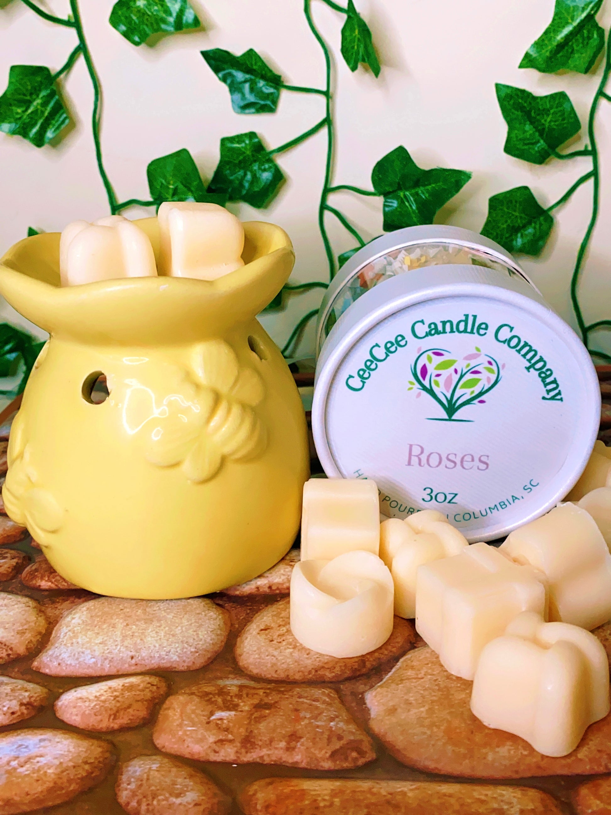 A Wax Melts Gift Box from CeeCee Candle Company sits on a stone surface with green ivy, featuring heart-shaped melts and a yellow warmer, creating an inviting aromatherapy atmosphere.