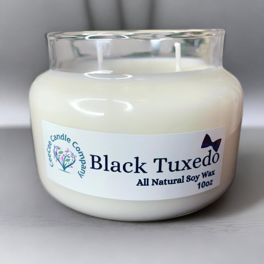 The Double Wicked Apothecary Soy Candle by CeeCee Candle Company is hand-poured in a clear glass jar labeled “Black Tuxedo, All Natural Soy Wax, 10oz” and features a small bowtie graphic on the label.