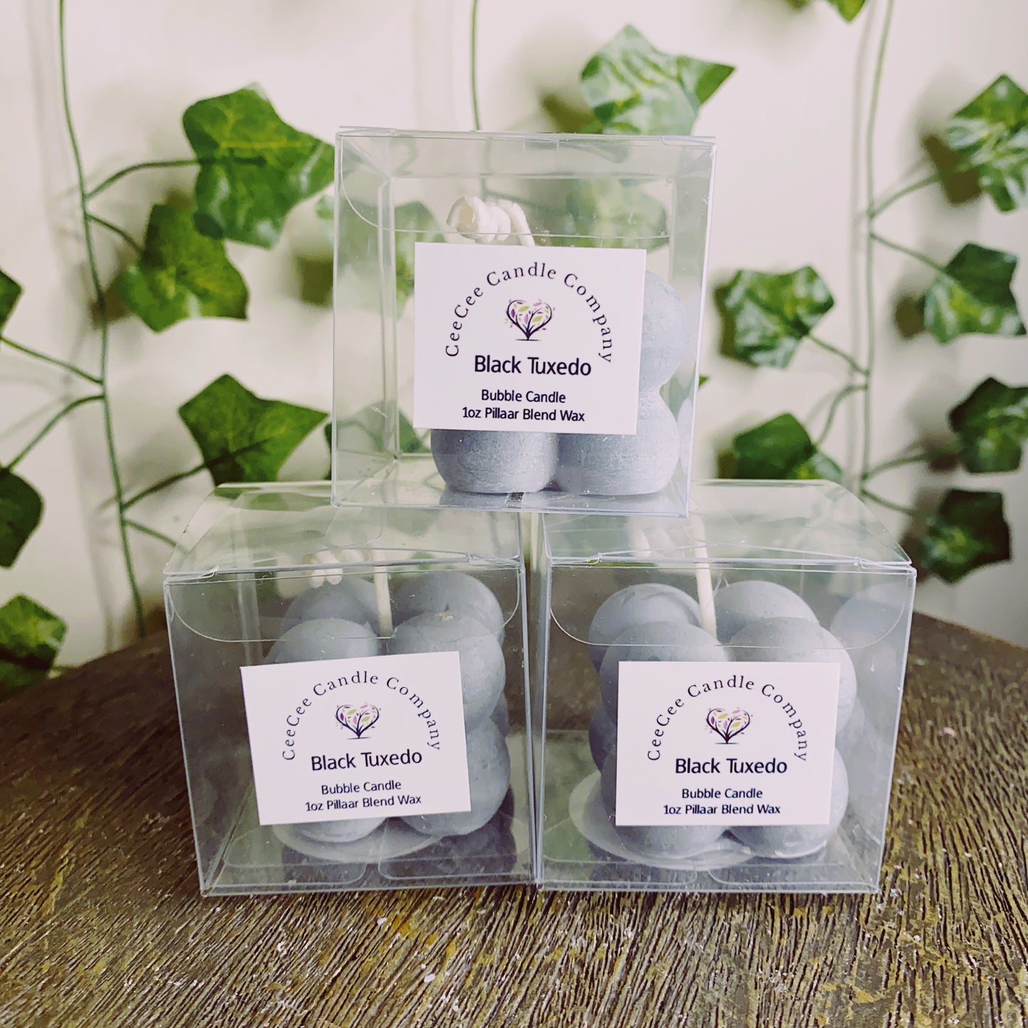 Three CeeCee Candle Company Bubble Candles with glass dishes are stacked on a surface with green ivy leaves in the background—ideal for pairing with your favorite fragrance oils.