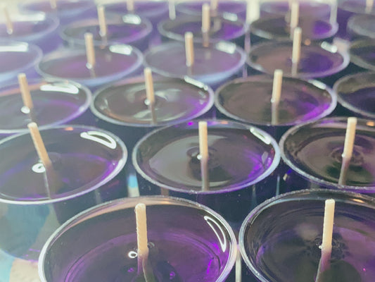 CeeCee Candle Company’s Soy Wax Tea Light Candles are eco-friendly and purple, featuring wooden wicks. Arranged in neat rows, their glossy surfaces reflect light, showcasing vibrant color and aromatherapy benefits.